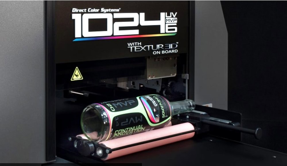Vibrant colored graphics being printed onto a glass bottle using a digital printing machine with LED UV technology for customized branding.