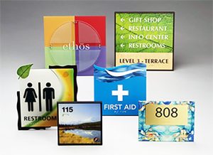Colorful sign group with restroom, first aid, room number, and directional signs for building navigation, designed for visibility and wayfinding.