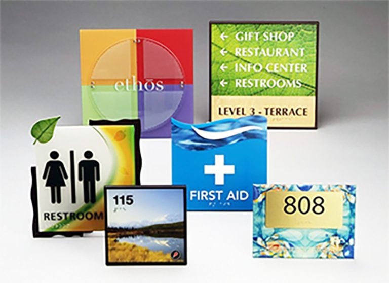 Colorful sign group with restroom, first aid, room number, and directional signs for building navigation, designed for visibility and wayfinding.