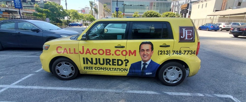 What Is A Vehicle Wrap And What Are The Benefits? 2 Calljacob.com campaign vehicle with bold signage, promotional contact details, and a professional image of a smiling man for legal injury consultation.