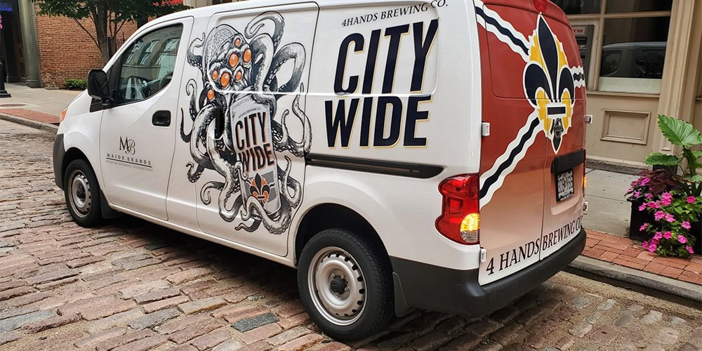 What Is A Vehicle Wrap And What Are The Benefits? 1 City wide branding on custom vehicle wrap for 4 Hands Brewing Co., featuring vibrant logo and graphic design for promotional advertising, professional signage, banners, and vehicle graphics.