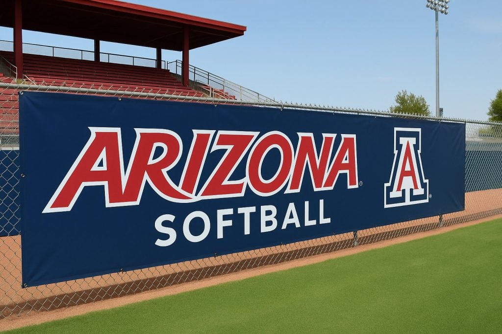 Arizona softball banner hanging on a chain-link fence at a sports field.