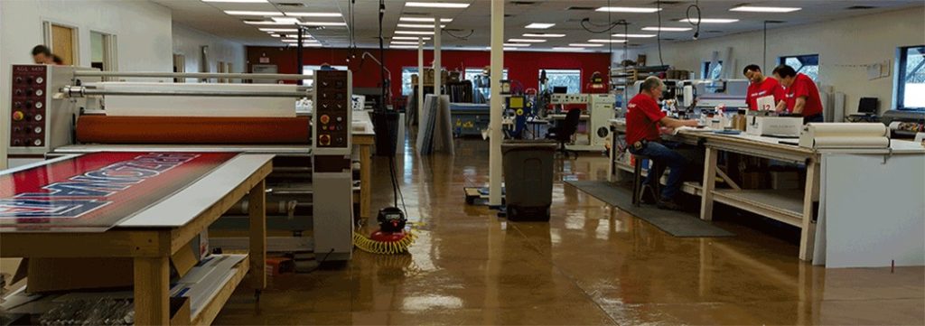 Sign-making workshop with printing and engraving equipment at Graphic Impact manufacturing facility.