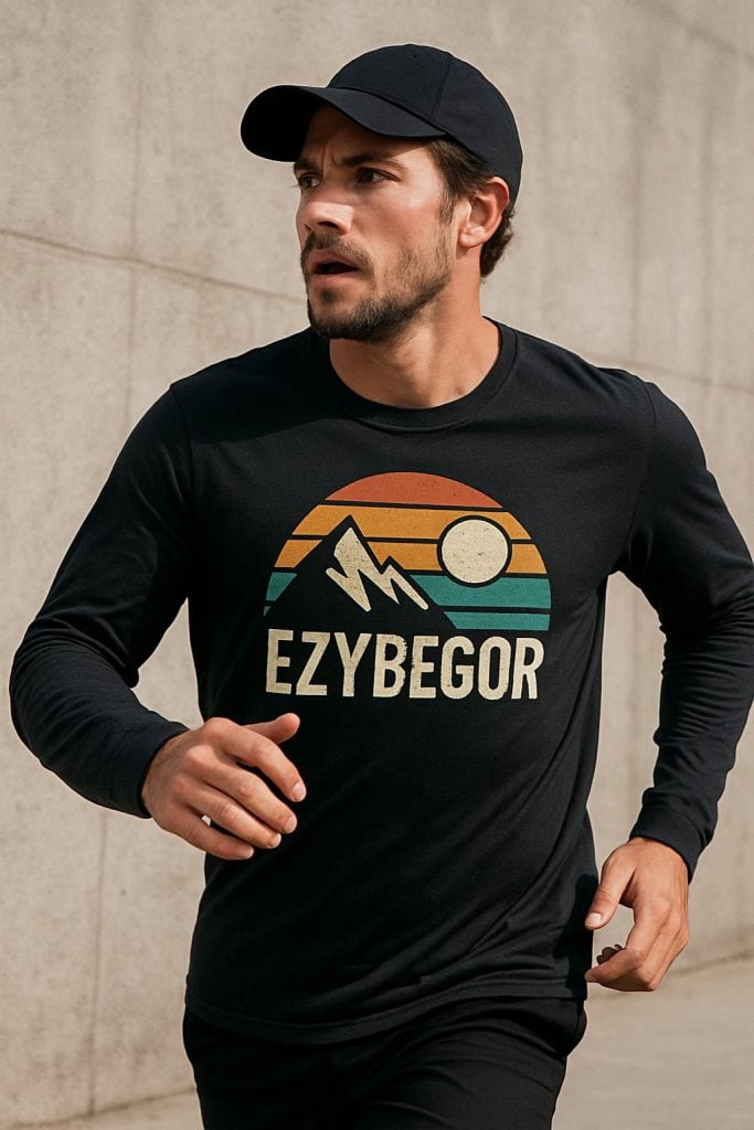 EZY Begor logo printed on a black athletic long sleeve shirt, featuring a mountain, sunset, and sun graphic, worn by a man jogging outdoors, promoting outdoor sports apparel and custom printing services.