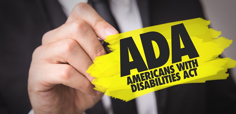 ADA Americans with Disabilities Act awareness sticker being held by a person in a business suit.