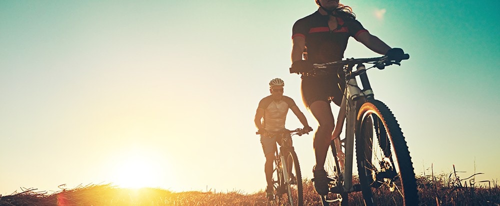 Riders cycling on a scenic trail during sunset, enjoying outdoor adventure and fitness.