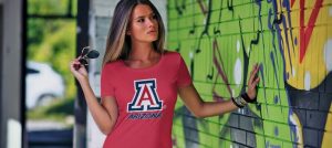Colorful graffiti wall with a woman wearing an Arizona Wildcats t-shirt holding sunglasses.