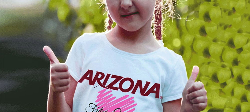 Arizona-themed girl wearing a white t-shirt with the Arizona logo, giving a thumbs-up sign outdoors.