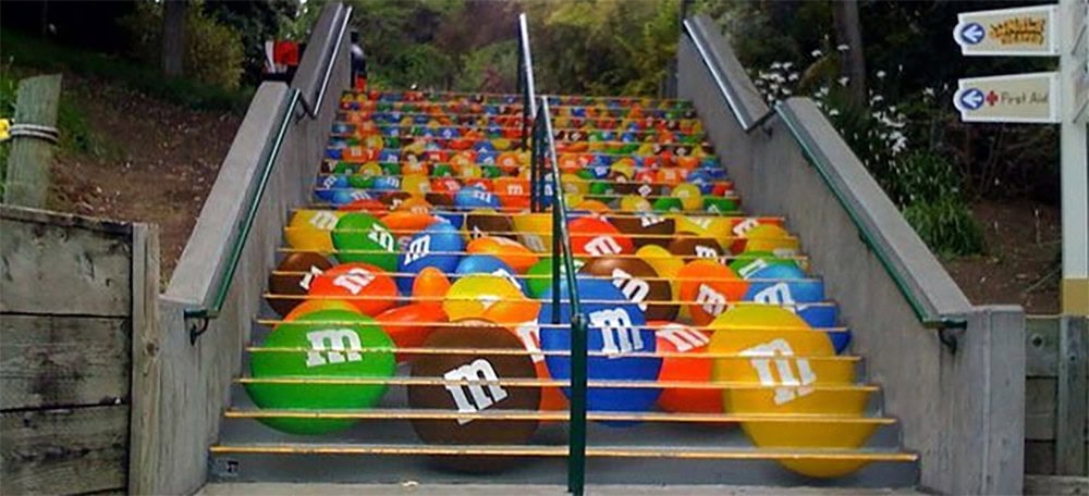 Colorful stairs decorated with M&M's themed artwork, vibrant and playful, outdoor setting, attention-grabbing design, perfect for attractions or entertainment venues.