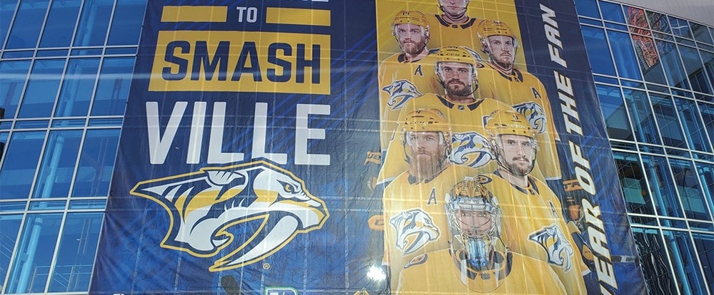 Vancouver Canucks hockey team banner featuring players in yellow jerseys hanging on a glass building for a sports event in Vancouver graphic impact signage services.