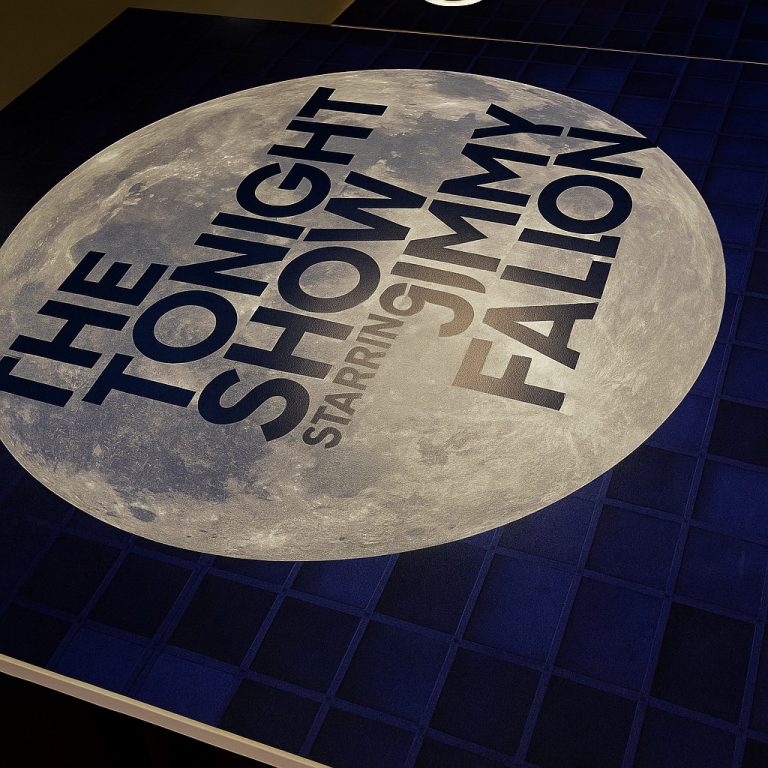 Sign with bold black text reading "The Tonight Show Starring Jimmy Fallon" displayed on a building exterior, promoting the late-night TV show.