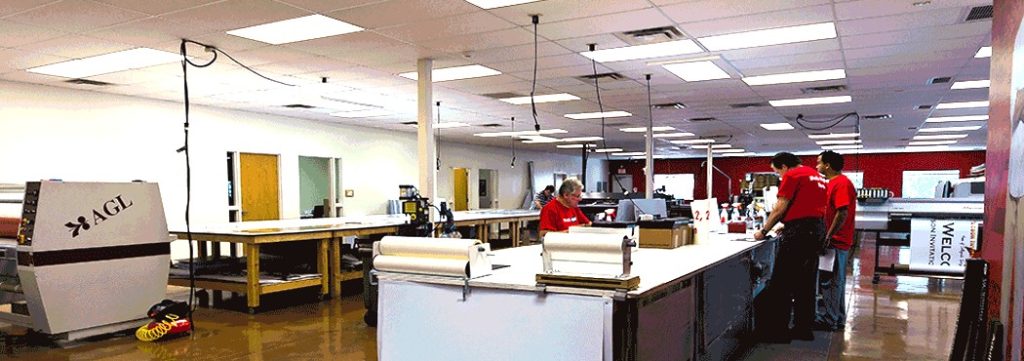 High-quality sign printing and engraving workshop at Graphic Impact, with staff assembling banners and signs in a large, well-lit production space.