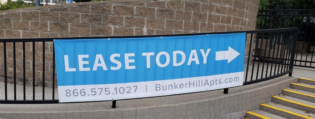 LEASE TODAY sign with contact information and arrow on a metal railing for commercial advertising and leasing promotions.