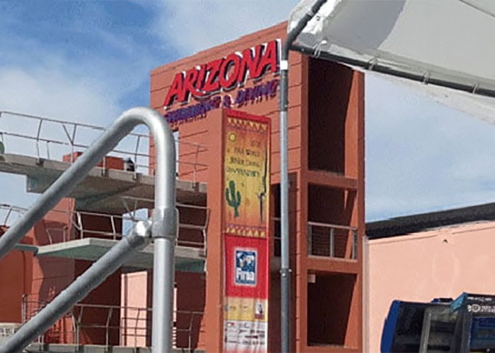 Arizona state welcome sign with colorful mural and cactus artwork at a construction site, showcasing custom signs and banners.
