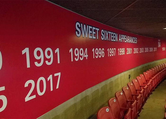1991 to 2017 milestone wall with years and a row of red stadium seats, celebrating the history of Sweet Sixteen appearances, in a sports venue or arena.