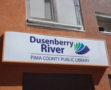 Dusenberry River Pima County Public Library sign featuring colorful logo and clear text.