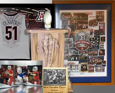 Colorful display of custom signs, banners, engraved plaques, and apparel at Graphic Impact showcasing sports memorabilia, trophies, and personalized awards.