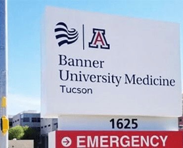 A large outdoor sign for Banner University Medicine Tucson featuring the university logo, address, and emergency signage.