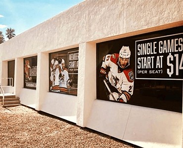 Vibrant outdoor signs and banners for sports events displayed on a building's exterior wall, showcasing custom graphics and professional engraving for promotional signage.