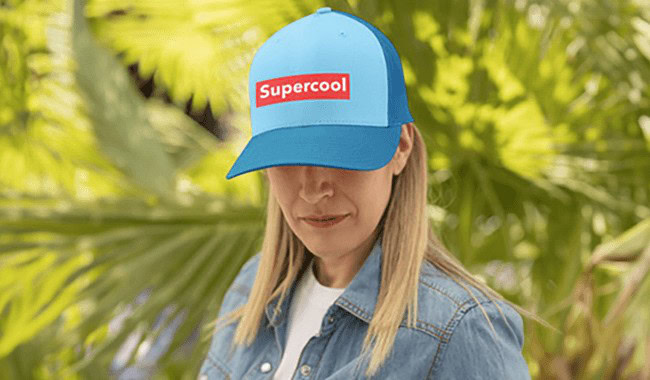 Bold blue cap with red and white "Supercool" logo worn by a woman outdoors among lush greenery.