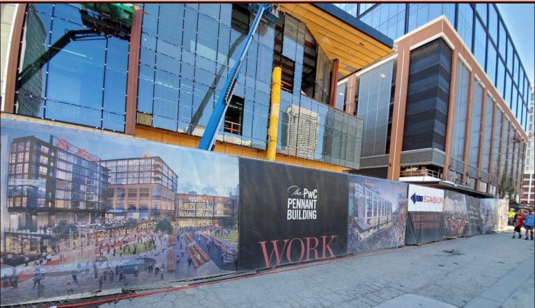 Modern construction site with branded signage for the upcoming Pennant Building project in an urban setting with glass facades.