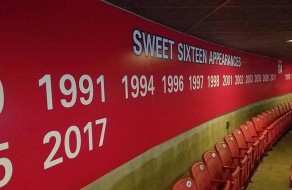 A colorful wall display showcasing the timeline of Sweet Sixteen basketball achievements from 1991 to 2017, with red seating along the curved wall in the background.