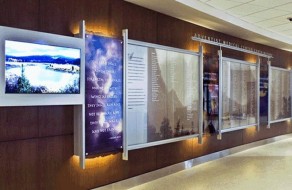 Modern interior wall display featuring digital screens and glass signage boards for effective communication.