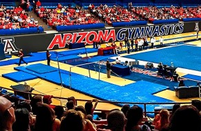 Arizona Gymnastics event at a professional arena, showcasing athletes, equipment, and spectators during a competitive meet.